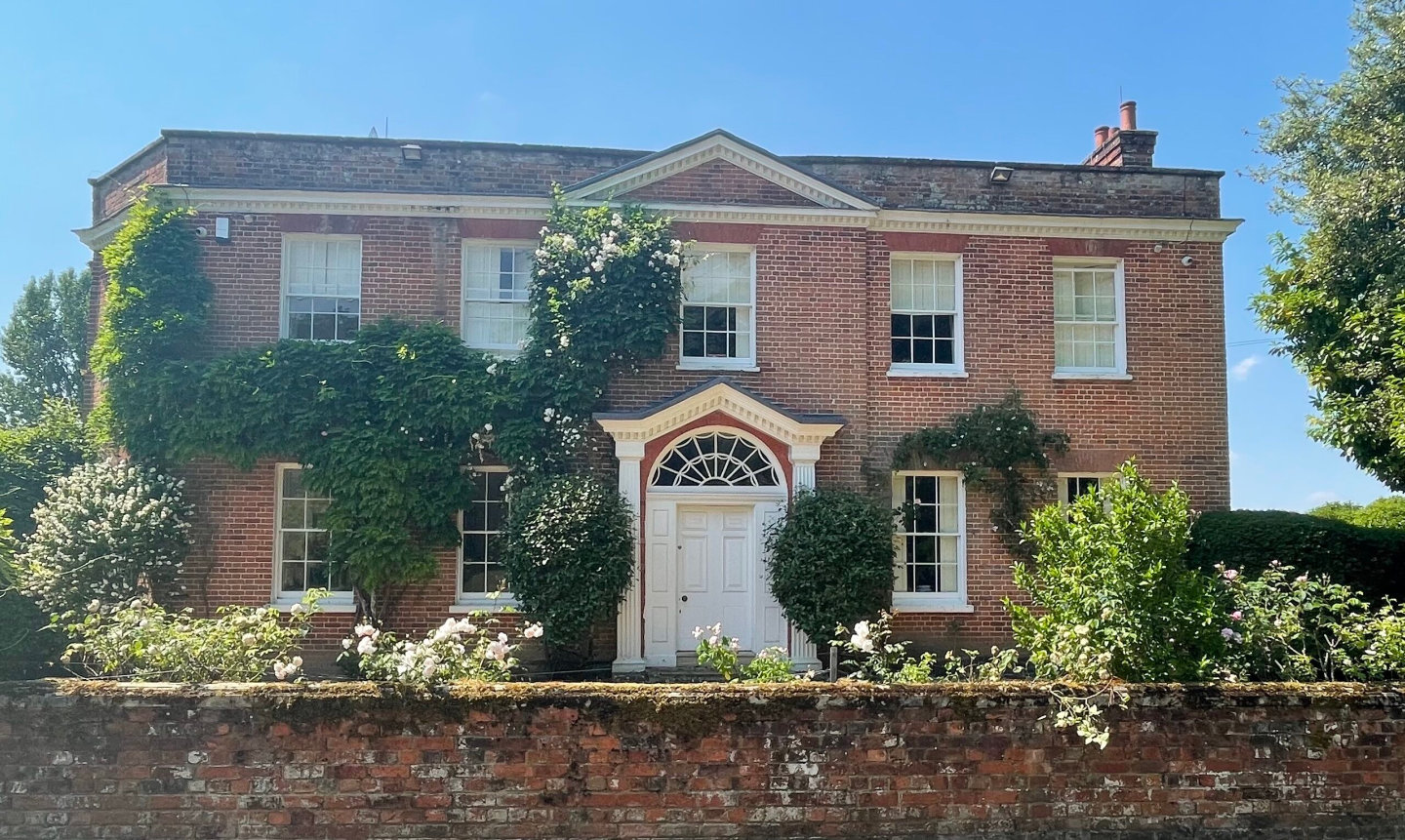 large, red brick house with large white doorway capped with arched window