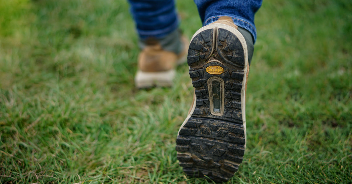 pair of feet in walking boots in the action of walking away on grass