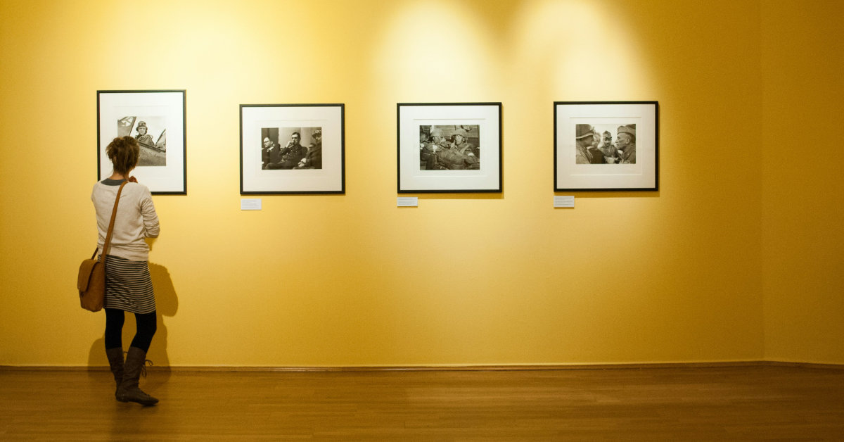 back of a lady looking at photos on the wall in a gallery