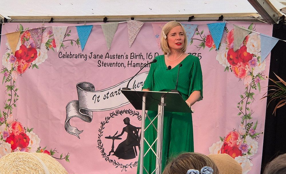 Lucy Worsley stands on stage at a podium during the Jane Austen celebrations at Steventon Fair