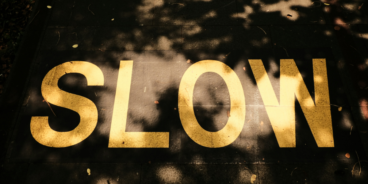 The word slow written in yellow paint on a road